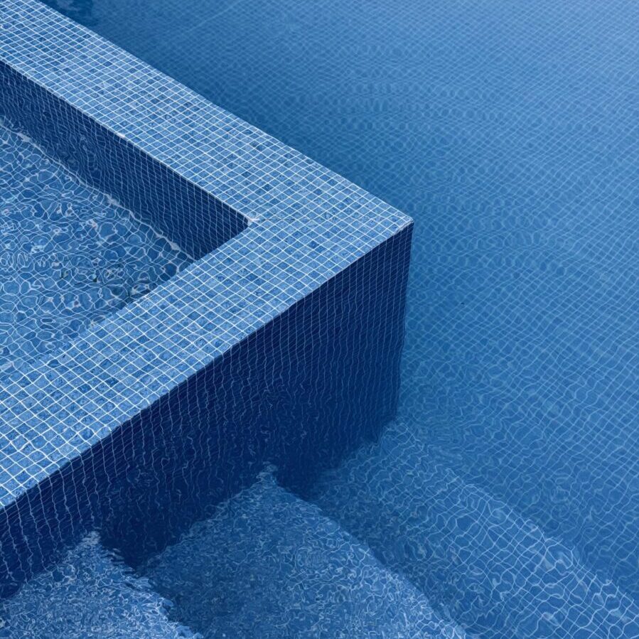 Abstract image of blue tiled pool edges with water ripples, exuding a minimalist and calming vibe.